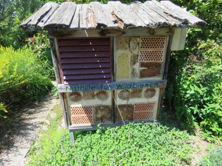 Das Insektenhotel im Umweltgarten Taufkirchen, Brutstätte für Insekten, z.B. Solitärbienen und -wespen, aus Holz mit einem Dach darin Ziegel mit Löchern und Pflanzenstengel, deren Inneres als Bruthöhle benutzt werden