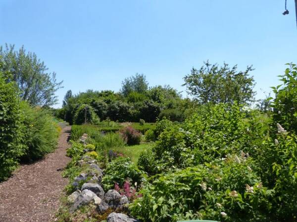 Umweltgarten  in Taufkirchen, Blick auf Blumenwiese und Rosengarten in Richtung Sinnespfad entlang eines Weges, viel Grün, bunte Pflanzen und Kräuter