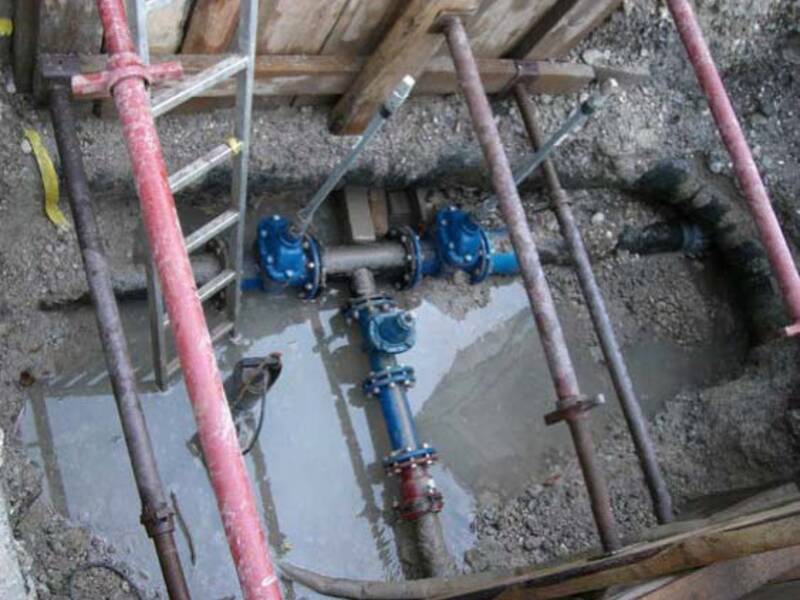 Bild zeigt ein blaues Wasserschieberkreuz in einer Baugrube in der Wasser steht