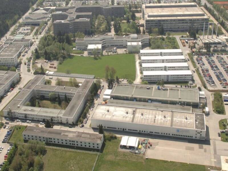 Luftansicht vom Technik und Innovationspark. Mehrere graue Bürogebäude umgeben von grünen Wiesen und Parkplätzen mit vielen parkenden Autos