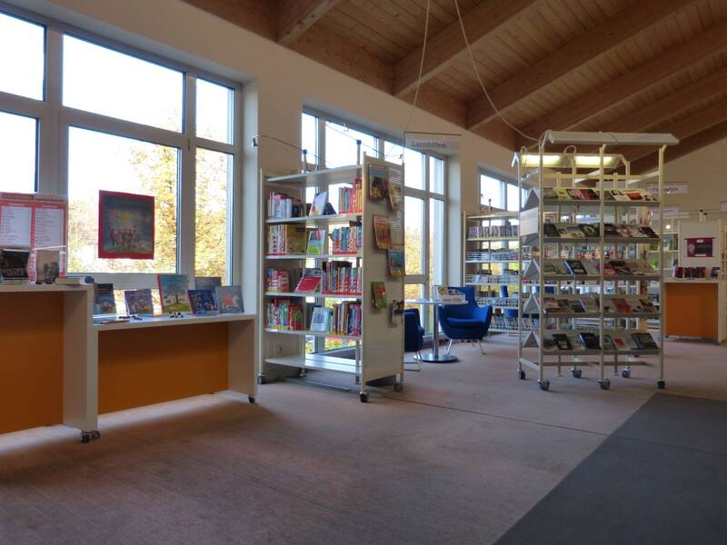 Gefüllte Bücherregale stehen vor einer Fensterfront