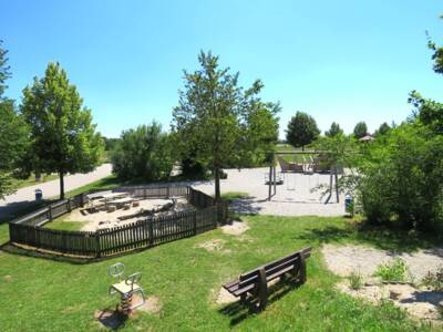 Spielplatz mit Bänke, Wippe und zwei Schaukeln um geben von Bäumen