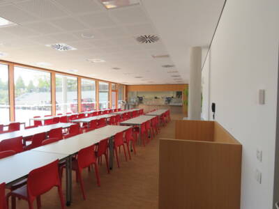 Tische und rote Stühle stehen vor der Ausgabestation für Essen in der Realschule